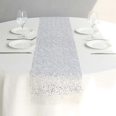 Silver sequin table runner on a white table setting with glassware.