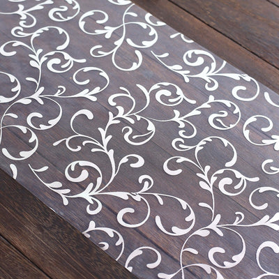 Elegant white floral vinyl table runner on dark wooden surface.