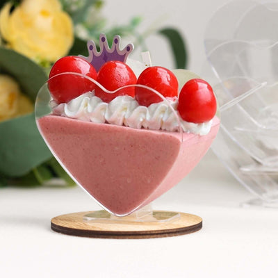 Heart-shaped dessert with cherries and whipped cream on a wooden base.