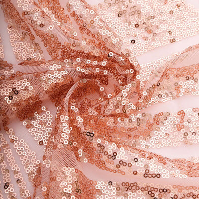 Rose gold sequin fabric draped elegantly, showcasing shimmer and texture.