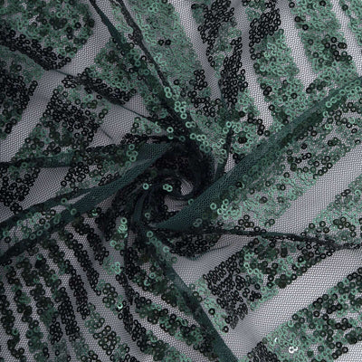 Green sequin fabric with a spiral design on a dark background.