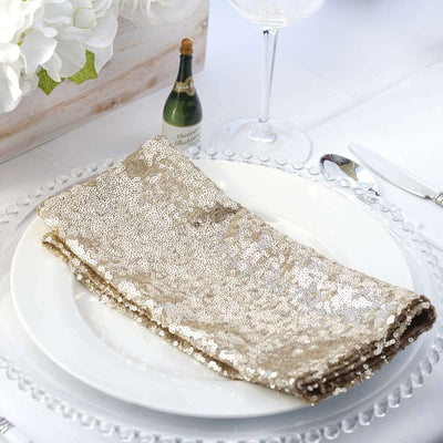 Gold sequin table napkin on a white plate, elegantly set for dining.