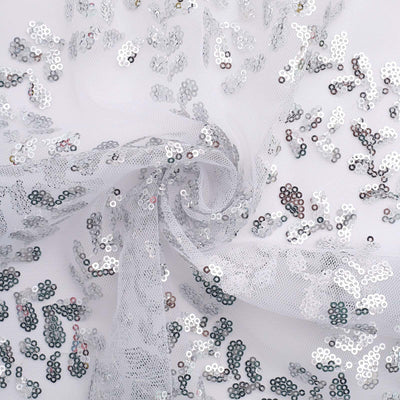 Silver sequined fabric with sheer lace overlay, perfect for crafting and fashion designs.