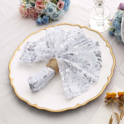 Silver sequin napkin on an elegant plate with floral decor in the background.
