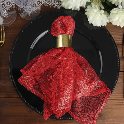 Red sequin napkin ring on a black plate, elegantly styled for dining.