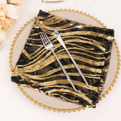 Black and gold sequined napkin on a decorative plate with silver cutlery.