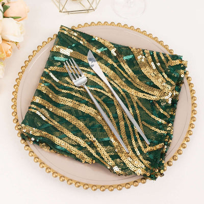 Green and gold sequin table napkin on a decorative plate with cutlery.