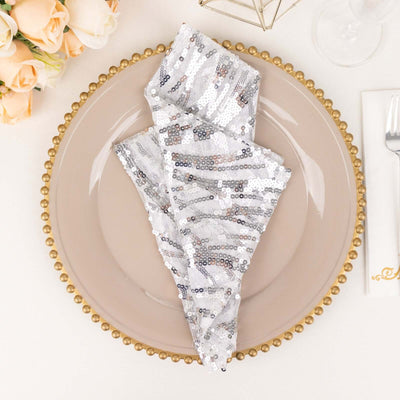 Silver sequin napkin elegantly folded on a decorative plate.