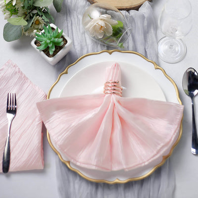 Elegant pink napkin elegantly folded on a decorative plate with dining utensils.