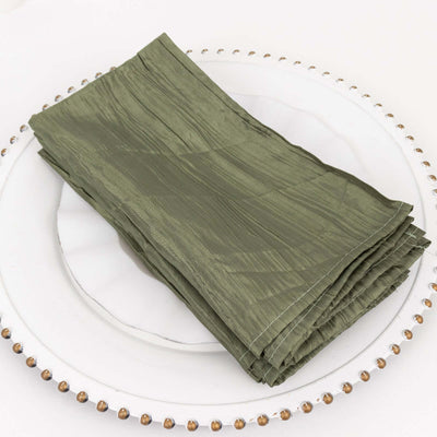 Olive green textured napkins stacked neatly on a decorative plate