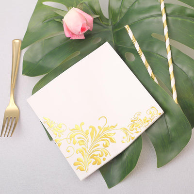Elegant white napkin with gold floral design, styled with a rose and straws.