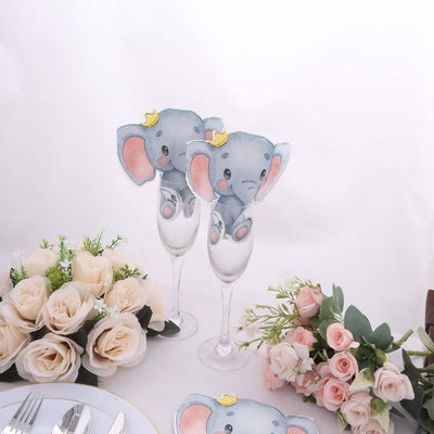 Elephant-themed party decorations on champagne flutes with floral arrangements.