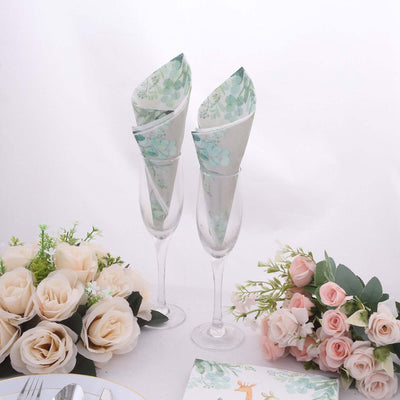 Elegant floral napkins in champagne glasses, styled with roses and greenery.