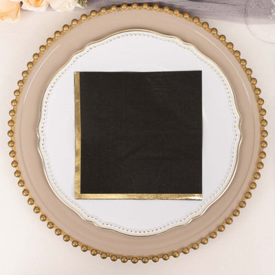 Black napkin with gold trim on decorative plate