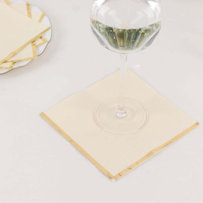 Elegant cream coasters with gold trim under a glass of water.