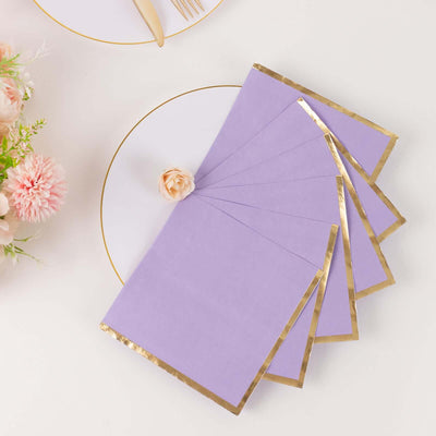 Lavender napkins with gold trim on a white plate, styled with a flower.