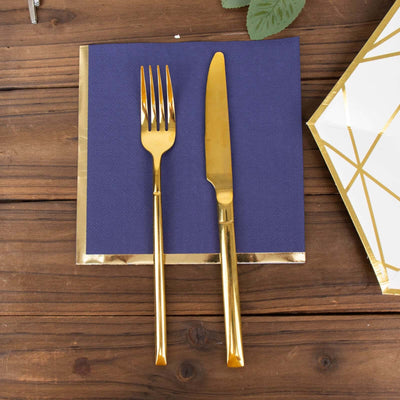 Gold fork and knife on a navy blue napkin with gold trim.