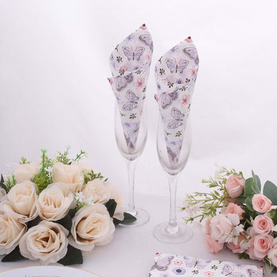 Elegant butterfly-themed napkin holders in champagne glasses with floral arrangements.