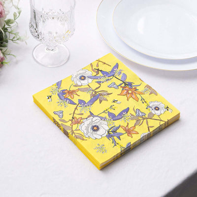 Yellow floral napkin on a table with a crystal glass and white plates.