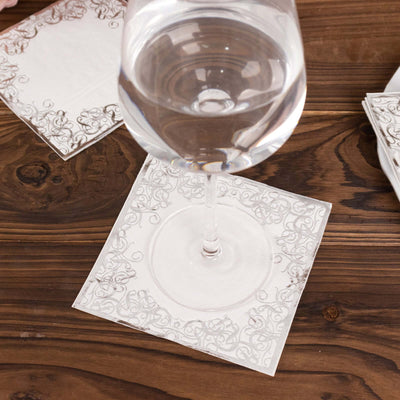 Elegant white paper napkin with decorative border under a glass of water.