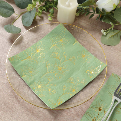Green floral napkin with gold accents on a clear plate.
