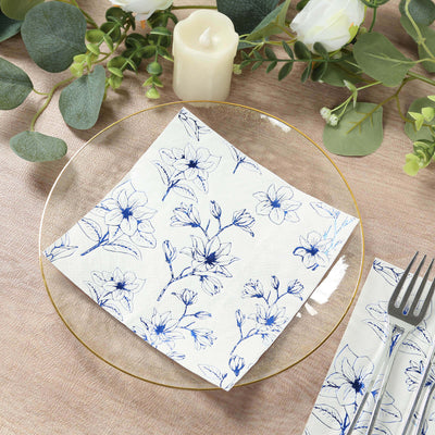 Floral patterned napkin on a clear plate with greenery and candle