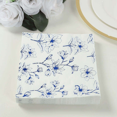 Floral printed napkin with blue magnolia design on a white background.