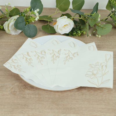 Elegant floral paper napkins on a plate with greenery backdrop.