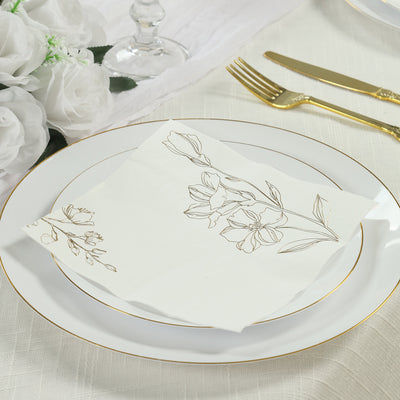 Elegant floral napkin on a white plate with gold trim, set for a dining experience.