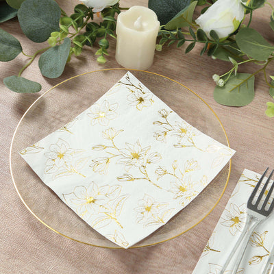 Elegant floral napkin on a decorative plate, surrounded by greenery and a candle.