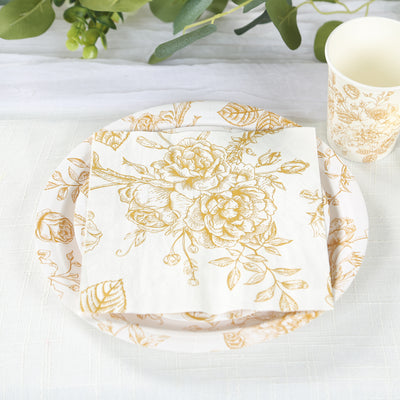 Floral-patterned napkin and plate set on a table with greenery decorations.