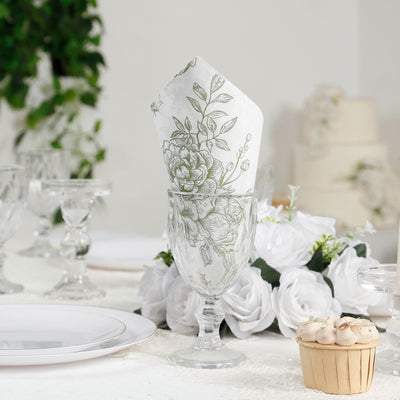 Elegant floral napkin in a glass on a dining table with white roses and dessert.