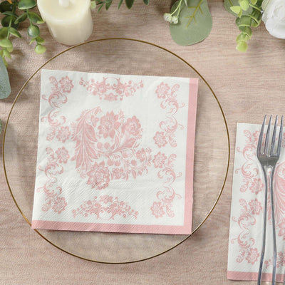 Pink floral napkin on a decorative plate with a fork beside it.