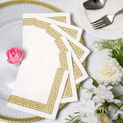 Elegant white napkins with gold Greek key design, arranged on a decorative plate.