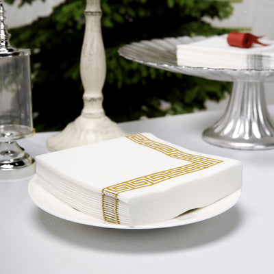 Elegant white napkins with gold geometric design on a plate.