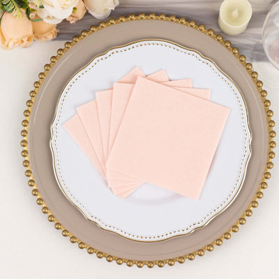 Pink paper napkins arranged on an elegant plate with a decorative rim.