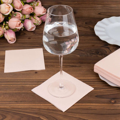 Clear wine glass on a pink napkin with a bouquet of roses in the background.