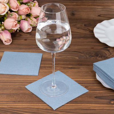 Elegant wine glass on blue napkin with flowers in the background.