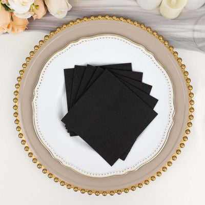 Black napkins stacked on an elegant plate, perfect for table settings.