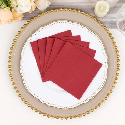 Red napkins arranged on a decorative plate for table setting.