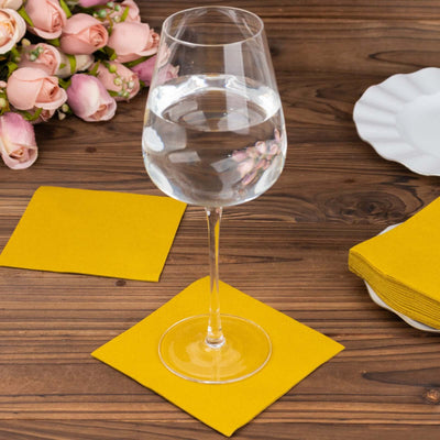 Water glass on yellow napkin with flowers in the background.