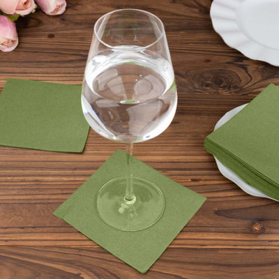 Green napkin under a glass of water on a wooden table.