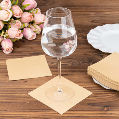 Clear wine glass filled with water on a wooden table with flowers and napkins.
