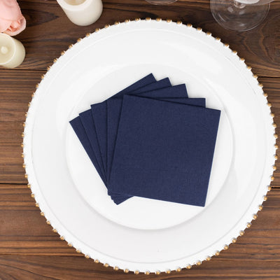 Navy blue napkins stacked on a decorative white plate.