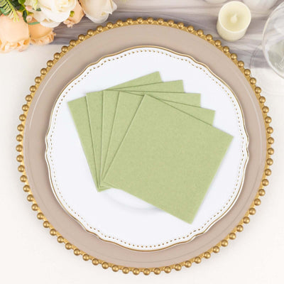 Green paper napkins stacked on an elegant plate with a decorative edge.