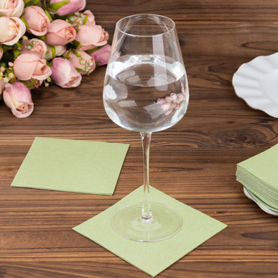 Wine glass filled with water on a green napkin with a bouquet in the background.