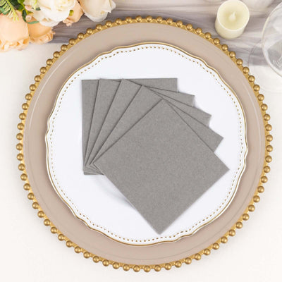 Gray napkins stacked on an elegant plate setting.