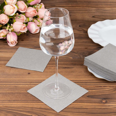 Clear glass of water on a gray coaster with a bouquet and plates in the background.