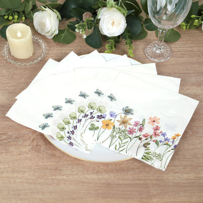 Floral decorative napkins arranged on a plate with candles and greenery.