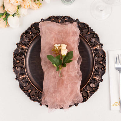 Elegant table setting with a pink napkin and floral arrangement on a decorative plate.